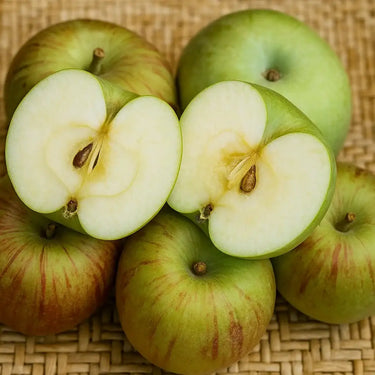 Beverly Hills apples with one sliced open on a woven surface. Fruit Trees Sold by Paradise Nursery.